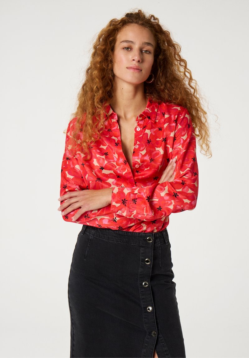 Rode bloemen blouse met lange mouwen, een kraag en knoopsluiting, gecombineerd met een zwarte denim rok met een zij-button ontwerp.