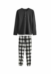 Czarna longsleeve henley z trzema guzikami, zestawiona z spodniami w czarno-białą kratę i elastycznym pasem. Miękka tekstura materiału.