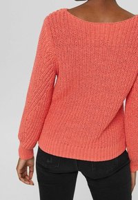 Korala wełniana sweter o luźnym kroju, szerokim dekolcie, długich rękawach i wzorze fakturowym. Ściągacze na mankietach i dole dodają szczegółów do projektu.