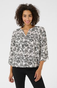 Blouse à imprimé floral noir et blanc avec décolleté en V et manches trois-quarts, fabriquée en tissu léger. Caractérisée par une coupe ample et des motifs texturés.