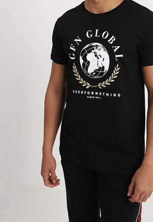 Camiseta negra con gráfico de un globo blanco, corona de laurel dorada y texto "GFN GLOBAL GOODFORNOTHING SINCE 2011" usada por una persona.