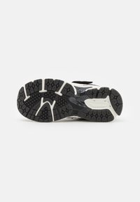 Semelle de chaussure de course noire avec caoutchouc texturé, motifs hexagonaux et accents blancs. Comprend de profondes rainures pour une adhérence et une durabilité accrues.