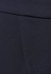 Dunkelblaues Strickgewebe mit glatter Textur und einem subtilen, gleichmäßigen Muster, mit einem weichen Bund oben.