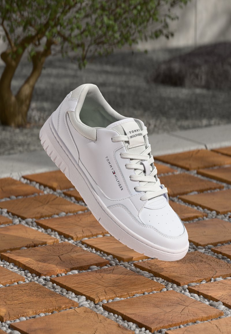 Białe skórzane sneakersy z perforowanym noskiem, okrągłymi sznurowadłami i wyprofilowaną podeszwą, z subtelnym logo po boku i na pięcie.