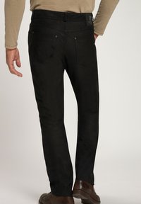 Schwarze Denim-Jeans mit einer taillierten Passform, die eine glatte Textur aufweisen, zwei Gesäßtaschen und ein Markenlabel am Bund haben.