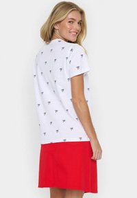 Balta T-kreksa ar melniem izdrukātiem tauriņiem, īsām piedurknēm, kombinēta ar sarkanu svārku. Gluda tekstūra, ikdienišķs dizains un normas piegriezums.