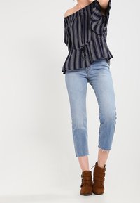 Námořnický off-shoulder top s vertikálními pruhy, peplum střih, v kombinaci s modrými destrovnými zkrácenými džíny a hnědými kotníkovými botami na přezku.