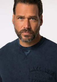 Ciemnoniebieska bluza z teksturowanej tkaniny, okrągły dekolt i tonalny haft z napisem "LAKE AREA WYOMING 1880". Prosty i casualowy design.