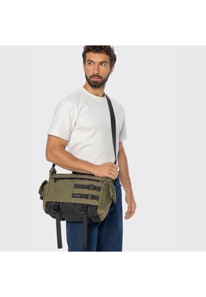 Zielona i czarna torba listonoszka wykonana z trwałego materiału, wyposażona w główną komorę na zamek błyskawiczny, regulowane paski oraz boczne kieszenie.