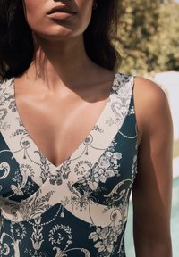 Vihreä-kermanvärinen kukkakuosiset hihattomat mekko, jossa on V-pääntie ja kontrastiset yksityiskohdat sekä sileä tekstuuri.