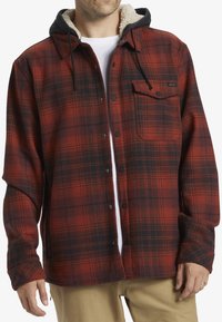 Red and black plaid flannel shirt with a shearling-lined hood, front pocket, and snap button closure. Long sleeves with button cuffs.