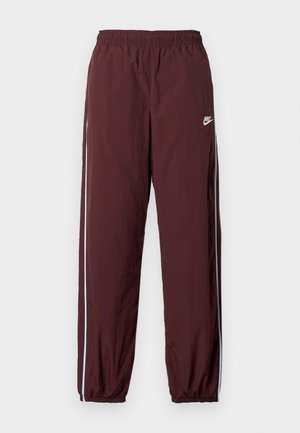 Bordové sportovní kalhoty s elastickým pasem, s jemným modrým bočním pruhem a malým bílým logem Nike na přední straně.