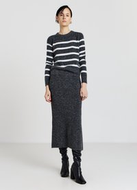 Gestreifter Pullover in Dunkelgrau und Weiß, kombiniert mit einem taillierten grauen Rock aus strukturiertem Stoff. Das Model trägt schwarze knopfhöhe Stiefel.
