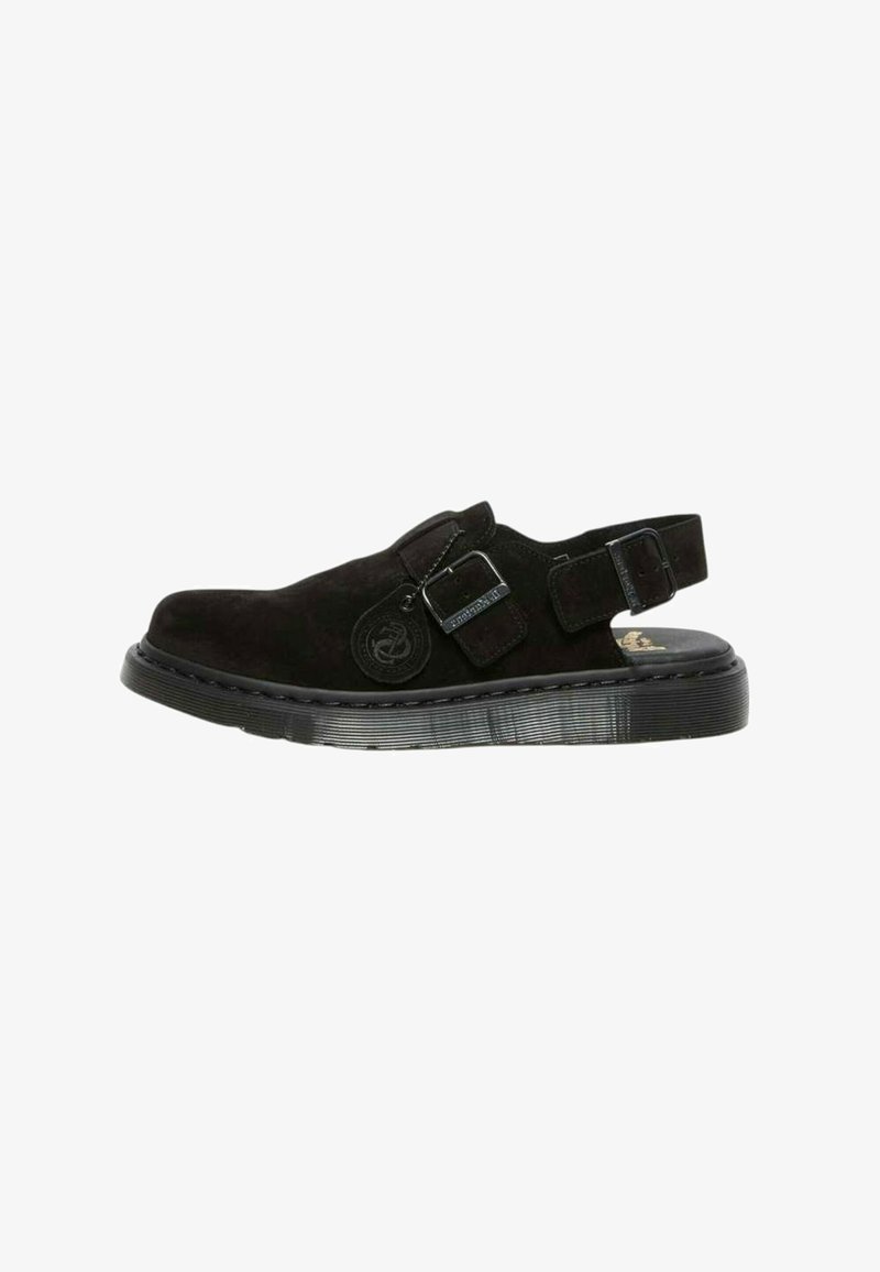 Svart mockasandal med justerbar spänne, stängd tå och tjock sula med strukturerad detalj.