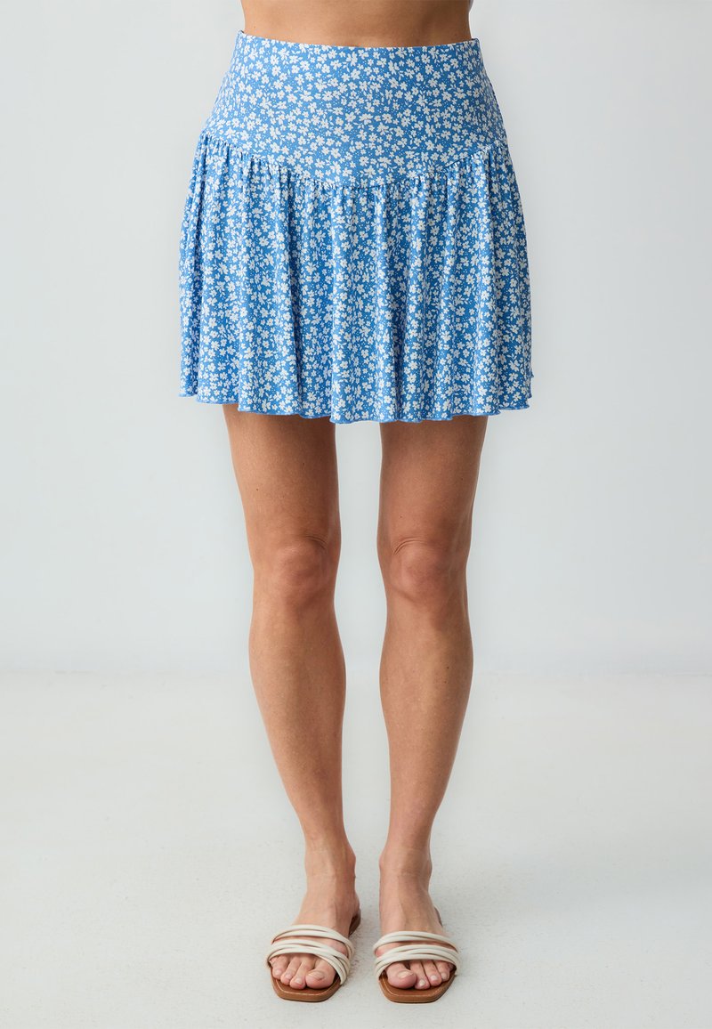 Blauer, floral gemusterter Minirock mit Falten-Design, verziert mit weißen Blumen auf einem hellblauen Hintergrund, aus weichem Stoff mit elastischem Taillenbund.