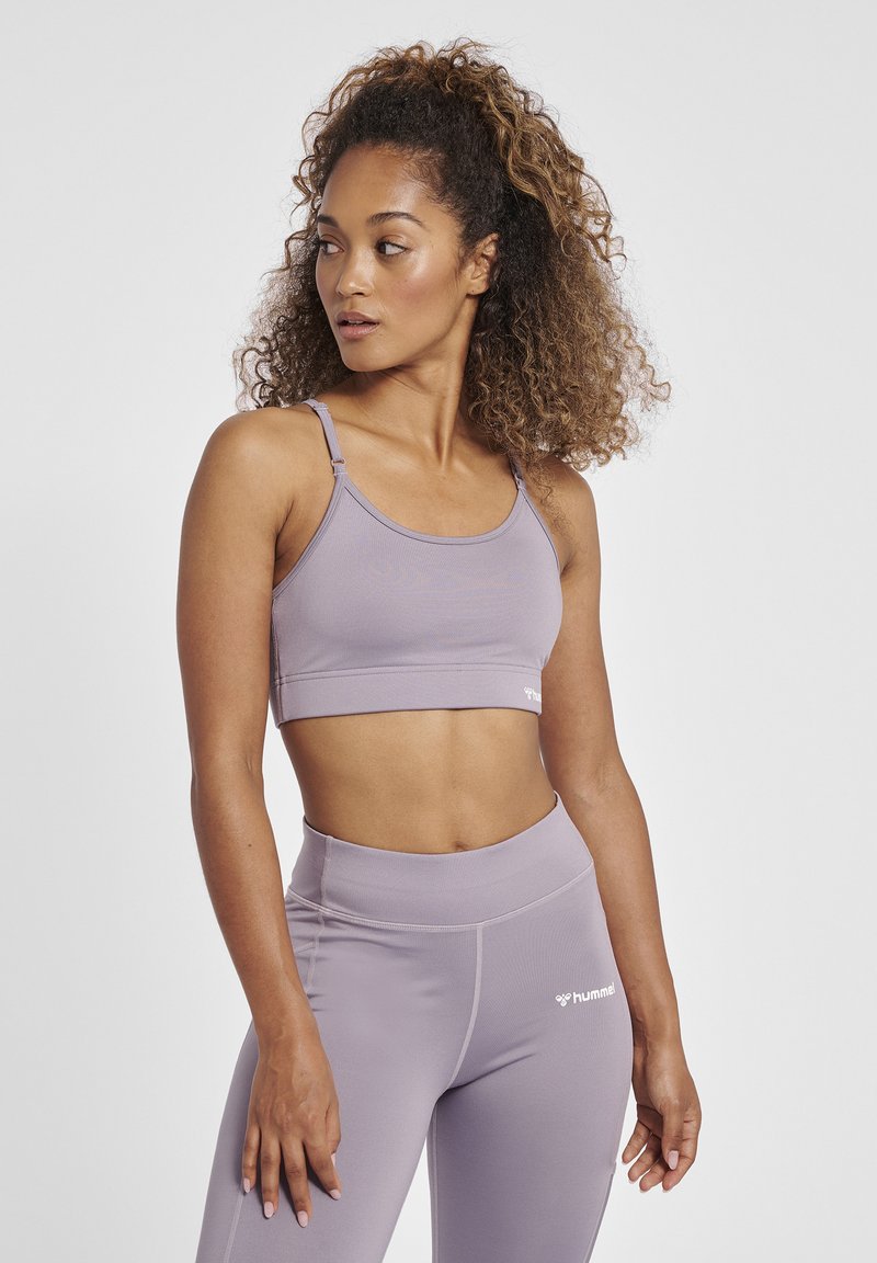 Licht paarse sportbeha met dunne banden en een elastische band aan de onderkant. Gecombineerd met bijpassende hoge leggings met subtiele branding.