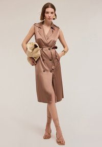Rochie din satin de culoare taupe, cu guler decupat, nasturi dublu încheiați, buzunare laterale și talie curea, stilizată cu sandale cu bretele.