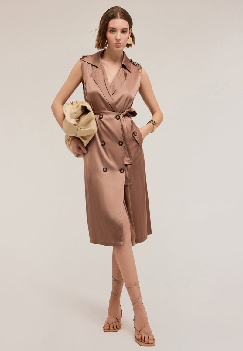 Rochie din satin de culoare taupe, cu guler decupat, nasturi dublu încheiați, buzunare laterale și talie curea, stilizată cu sandale cu bretele.