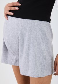 Shorts grigi a coste realizzati in morbido tessuto, con una vestibilità comoda e cuciture laterali discrete, dotati di una cintura liscia.