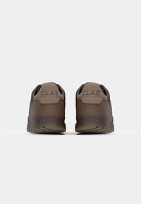 Brown athletic shoes with a textured fabric upper and smooth leather accents. Features a rubber sole and embossed "CLAE" logo on the heel.