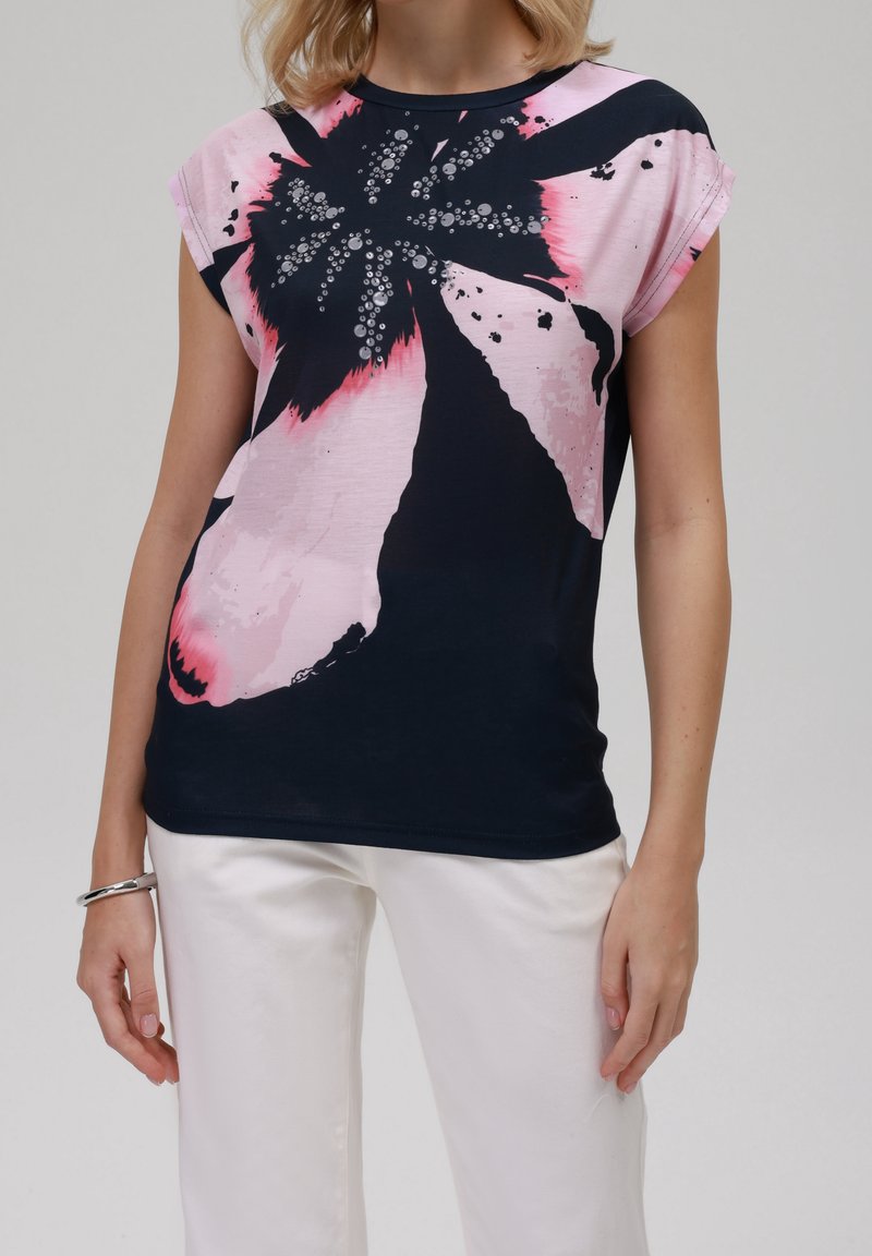 Mörkblå t-shirt med en rosa blommönstring, med rund halsringning och korta ärmar. Slät tyg med livlig färgkontrast.