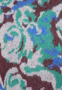 Tessuto a maglia con un motivo floreale in verde, blu e bordeaux su sfondo bianco, caratterizzato da una consistenza morbida e dettagli intricati.