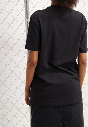 Schwarzes Baumwoll-T-Shirt mit kurzen Ärmeln und entspannter Passform. Glatte Textur, Rundhalsausschnitt und Nahtabschlüsse. Keine sichtbaren Grafiken oder Muster.