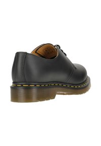 Scarpa nera in pelle con punta arrotondata, lacci frontali e suola in gomma texture con dettagli di cucitura gialla.
