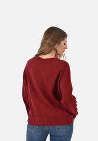 Pullover in lana marrone con orlo e polsini a coste, caratterizzato da un classico scollo rotondo e dettagli testurizzati lungo le maniche.