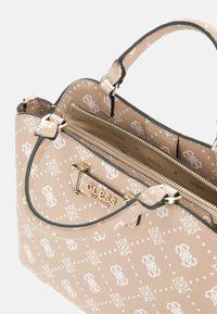 Borsa Guess beige con motivo a logo bianco, placca dorata del marchio, manici doppi e tasca con zip visibile all'interno.