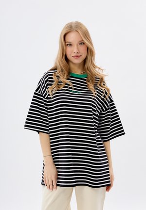 Zwart-wit gestreepte oversized t-shirt met een groene ribbelkraag en een klein groen logo. Korte mouwen en van zacht katoen.