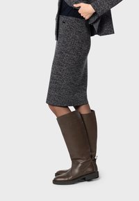 Gonna aderente alle ginocchia in tessuto grigio testurizzato abbinata a stivali alti in pelle marrone con punta arrotondata e tacco leggero.