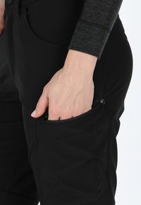 Svarta mjuka skalbyxor med en zip-fick, som har en slank passform och en mjuk yta. Logotypdetalj synlig vid fickan.