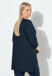 Mörkblå långärmad tröja med avslappnad passform, sidoslitsar och en mjuk textur. Har rund halsringning och mjukt tyg som är lämpligt för lager-på-lager.