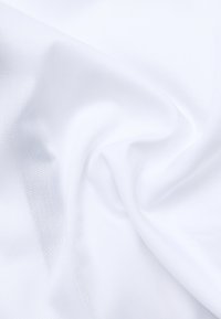 Biały materiał o gładkiej fakturze, ukazujący delikatny połysk i subtelny wzór tkaniny, złożony tak, aby pokazać jego miękkość i zdolność do układania się.