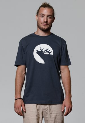 Marineblauwe katoenen T-shirt met korte mouwen, met een wit silhouet van een hert tegen een volle maan ontwerp op de voorkant.