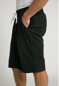 Pantalones cortos negros con una cinturilla elástica ajustable, que cuentan con bolsillos laterales y un bolsillo trasero con botón, fabricados en un tejido ligero con una sutil textura.