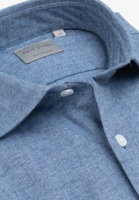 Jasnoniebieska koszula z guzikiem, wykonana z teksturowanej tkaniny w wzór jodełki, z kołnierzykiem i metką z napisem "DAN JOHN REGULAR."