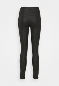 Svarta leggings med en texturerad mönster, hög midja och kroppsnära design. Slätt material sträcker sig till ankeln utan synliga sömmar.