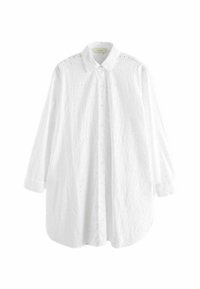 Longue blouse blanche boutonnée avec broderie œillet florale subtile, manches longues bouffantes, col et ourlet arrondi.