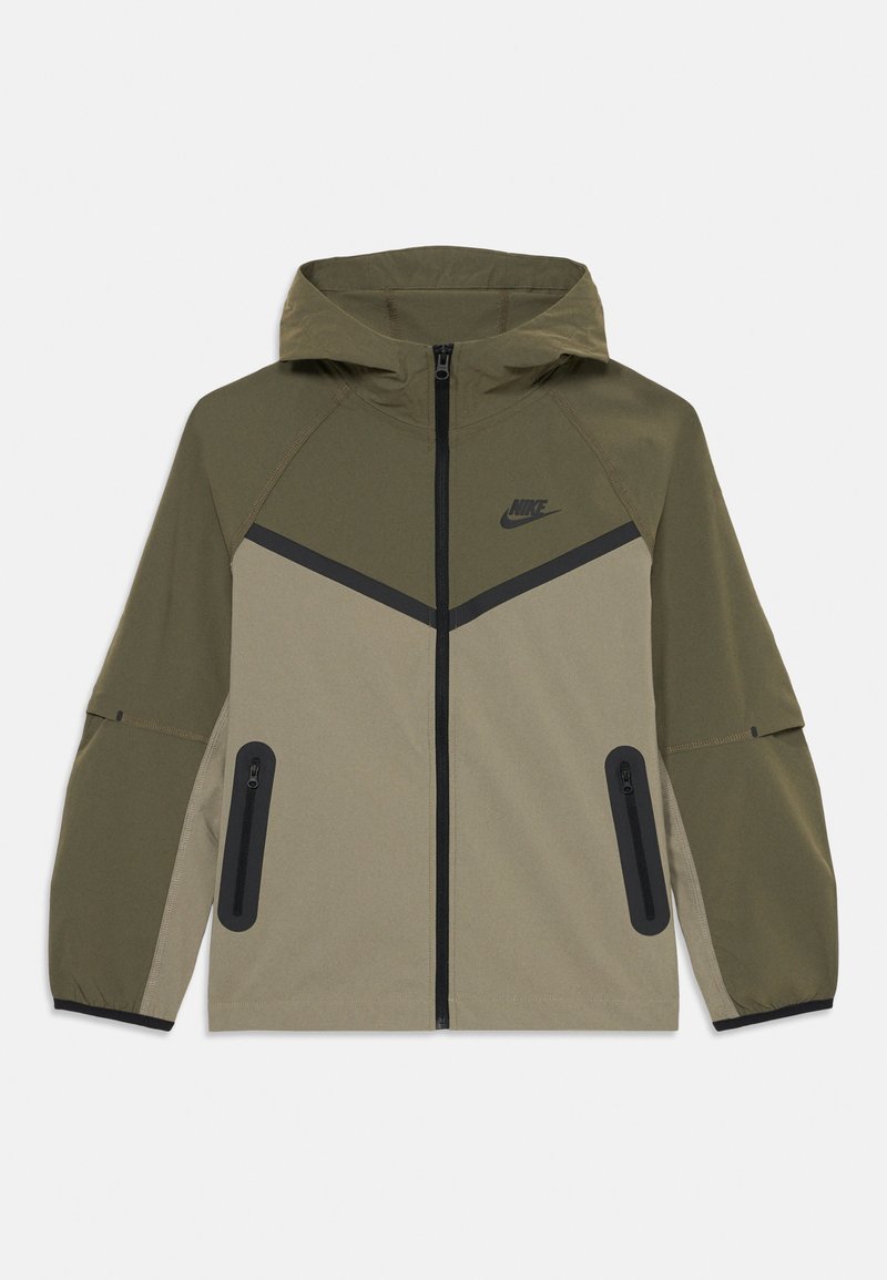 Hooded Nike jacket in olive and beige with front zipper, black chevron detail, zippered pockets, and elastic cuffs.