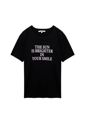 Mustaa puuvillapaitaa, jossa on lyhyet hiat. Edessä keskellä on suuri valkoinen teksti, joka sanoo "AURINGON VALO ON KIRKAAMPI HYMYSTÄSI".