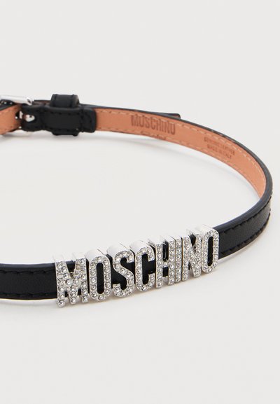 Μαύρο δερμάτινο κολιέ τύπου τσόκερ με γράμματα από ασημί στρας που σχηματίζουν τη λέξη "MOSCHINO" και ρυθμιζόμενο κούμπωμα με αγκράφα.