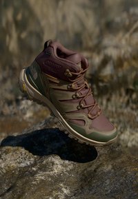Fjellstøvel med to-farget design i dempet lilla og grønn, laget av syntetisk materiale med strukturert detaljer og synlig snøringssystem.