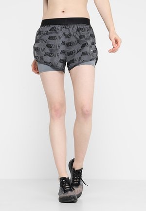 Grå Nike shorts med elastisk talje, prydet med gentagne "NIKE AIR" logoer og en indre foring. Båret med sorte sportsko.