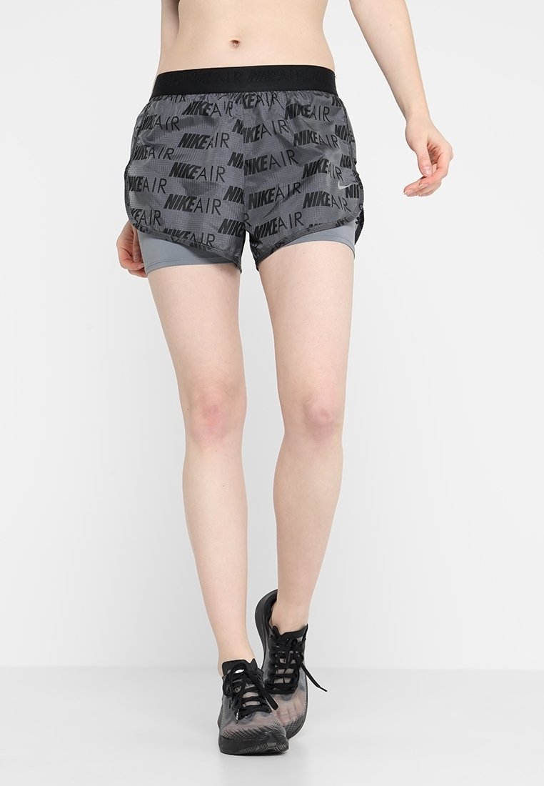 Grå Nike-shorts med resårmidja, med upprepade "NIKE AIR"-logotyper och innerfoder. Bärs med svarta träningsskor.