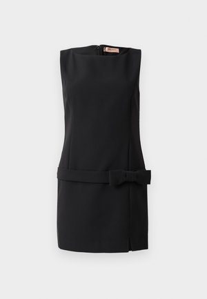 Black sleeveless dress in smooth fabric, featuring a bow accent on the waist, zip back closure, and a side slit. Minimalist design.