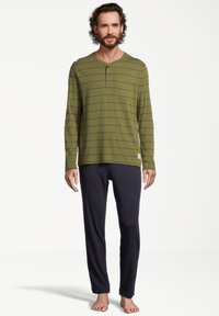 Vihreä pitkähihainen henley-paita, jossa on tummansinisiä vaakaraitoja ja rintatasku, yhdistettynä tummansinihin yöpantsareihin; puuvillakangasta, rento malli.