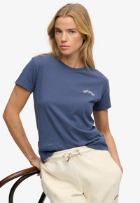 Marineblå bomuldst-shirt med rund halsudskæring og korte ærmer samt en hvid "Superdry"-logo på brystet.