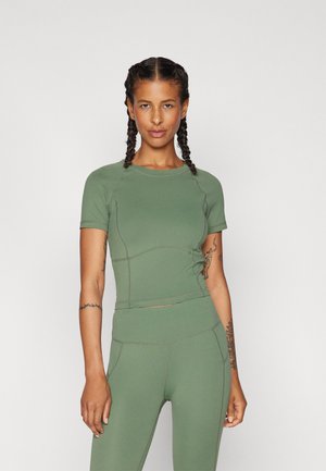 Olijfgroen sporttop, korte mouwen, aangesloten ontwerp, zachte textuur, zichtbare stikdetails. Gecombineerd met bijpassende olijfgroene leggings.
